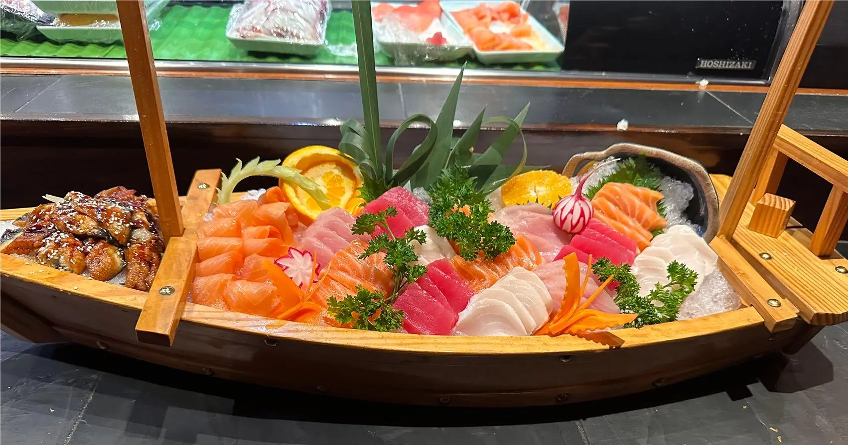 Wooden sashimi boat platter filled with assorted fresh raw fish on crushed ice at Ohayo Sushi, a Japanese Restaurant in Lewisville